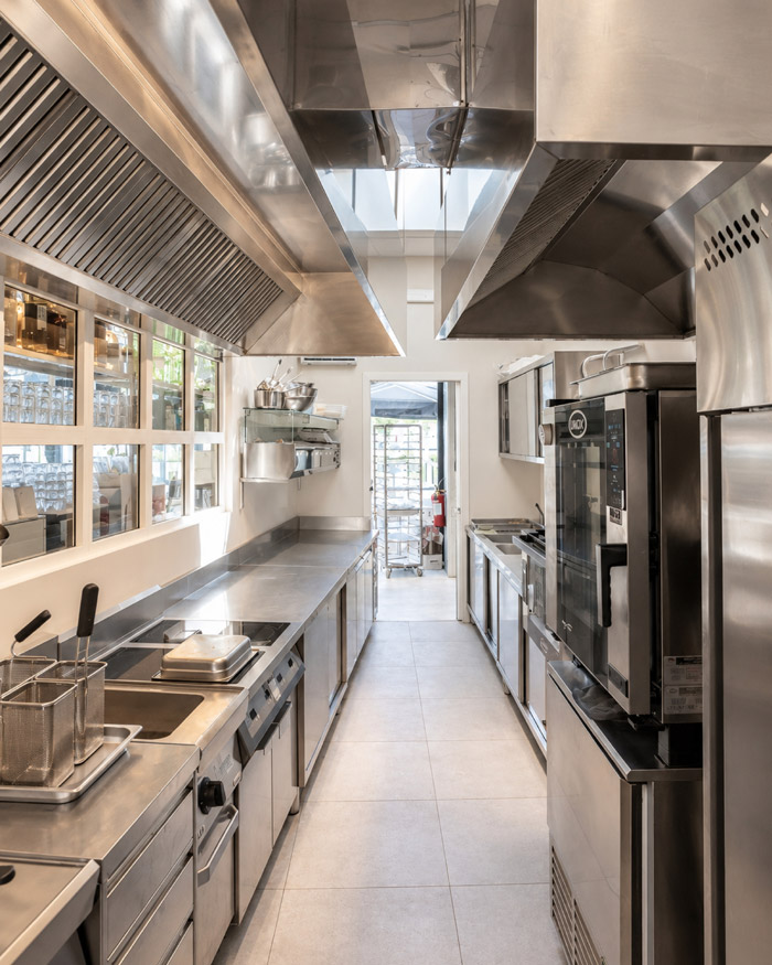 Grande impianto di cucina industriale con forni Unox, isola di cottura e cappe di aspirazione